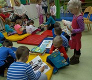 Sala Muminków i kilkoro przedszkolaków oglądają książeczki. Kilkoro dzieci siedzi na materacach, a i