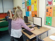 Dwie dziewczynki stoją przed komputerem i sprawdzają w internetowym słowniku znaczenie słów po angie