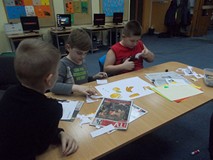 Dzieci siedzą przy stole i wycinają elementy pracy