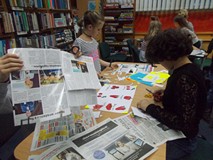 Dzieci siedzą przy stoliku i pracują nad plakatem