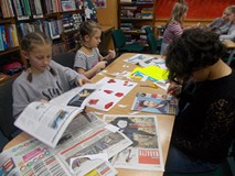 Dzieci siedzą przy stoliku w drużynie i wykonują prace plastyczną