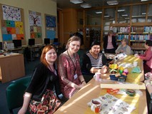 Panie siedzą przy stolach a trzy bibliotekarki pozują do wspólnego zdjęcia