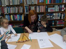 Bibliotekarka pomaga chłopcu w pracy plastycznej
