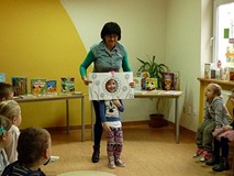 KSIĄŻKA Z DZIURĄ - do zabawy. Na zdjęciu dziewczynka wciela się w wiosenny kwiat