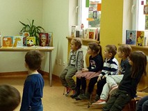 Dzieci rozwiązują książkowe zagadki, prezentowane przez biibliotekarkę