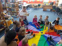 Bibliotekarka pokazuje dzieciom ksiązkę ze zgadywankami