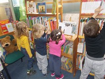 Czworo dzieci stoi przy regałach wybierając ksiażeczki