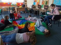 Bibliotekarka czyta ksiązkę dzieciom siedzącym na chuście