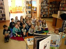 Dzieci siedzą na chuście animacyjnej, a Pani Wiola wita się z dziećmi