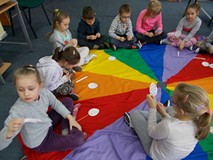 Dzieci siedzą na chuście i ozdabiają pisanki