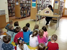 Dzieci siedzą na chuście, a na stole stoi dziwna skrzyneczka. To teatrzyk Kamishibai, w którym dziś 