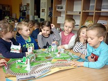 Dzieci oglądają książkę, która zamienia się w matę do zabawy - WIELKA PODRÓŻ TOMKA