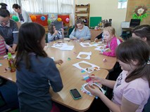 Dzieci siedzą przy stole wykonując ozdoby świąteczne