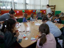 Dzieci przy stołach wykonują pracę plastyczną