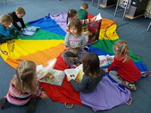 Dzieci siedzą na chuście animacyjnej z książkami