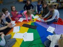 Dzieci siedzą na chuście i wyklejają alfabet Braille'a