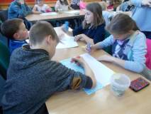 Dzieci rysują prace plastyczne przy stołach