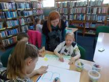 Bibliotekarka obserwuje postępy pracy plastycznej dziecka