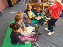 Dzieci siedzą na materacach i oglądają ksiażki