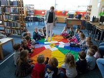 Bibliotekarka chodzi wokół dzieci na chuście i czyta wiersz