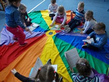 Dzieci siedzą na chuście i oglądają książki