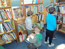 Trzech chłopców wyciąga książki z regału