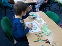 Chłopiec siedzi przy stole i koloruje obrazki