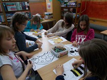 Dzieci siedzą przy stole i kolorują obrazki