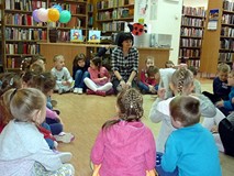 Bibliotekarka i dzieci siedzą w kręgu. Chętni - recytują wierszyki