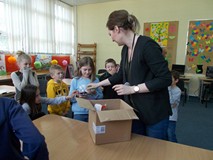 Bibliotekarka rozdaje dzieciom nagrody za udział w konkursie czytelniczym