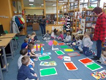 Bibliotekarka wyjaśnia dzieciom zasady zadania dotyczącego gry