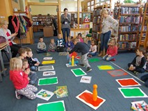 Chłopiec doszedł do mety i bierze chorągiewkę. Bibliotekarka i nauczycielka biją brawo