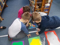 Grupa dzieci układa obrazek z rozsypanych elementów