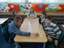 Dzieci siedzą przy stole i grają w grę