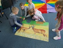 Grupa dzieci układają puzzle z wizerunkiem saren