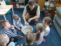 Leśniczy obserwuje poczynania dzieci w rozpoznawaniu tropów zwierząt