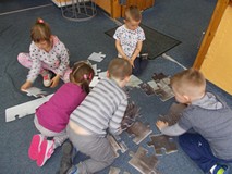 Dzieci układają wspólnie puzzle z wizerunkiem wydry