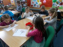 Dzieci siedzą przy stole i kolorują ptaki