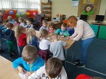 Dzieci kolorują ilustracje, a bibliotekarka wspomaga ich pracę