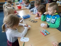 Dzieci siedzą przy stole i kolorują zwierzęta