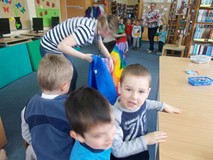 Bibliotekarka trzyma kolorowy tunel przez który przechodziły dzieci