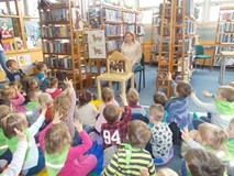 Dzieci patrzą w stronę bibliotekarki, która czyta im historię