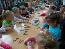 Dzieci siedzą przy stole i kolorują obrazki