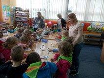 Dzieci kolorują ilustracje, a bibliotekarka wspomaga ich pracę