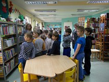 Uczniowie przy regałach  z wierszami dla dzieci i książkach z dużymi literami dla początkujących
