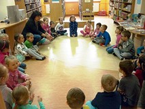 Dzieci i bibliotekarka siedzą w kręgu, po turecku, i słuchają recytacji bardzo śmiesznych wierszyków