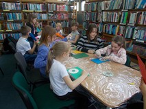 Dzieci siedzą przy stole i wykonują pracę plastyczną