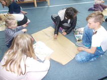 Dzieci wspólnie w drużynie wyszukują informacje, które zapisują na szarym papierze