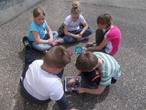 Czworo dzieci siedzi w kręgu i grają w grę planszową