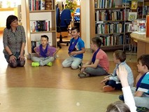 Dzieci siedzą w kręgu - bibliotekarka moderuje zabawę w skojarzenia